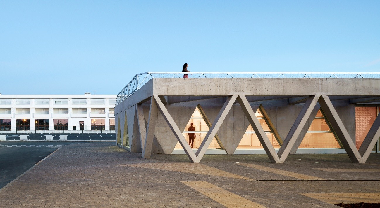 Vista exterior del Edificio Polivalente del Puerto de Ayamonte, con geometría de hormigón y terraza superior.